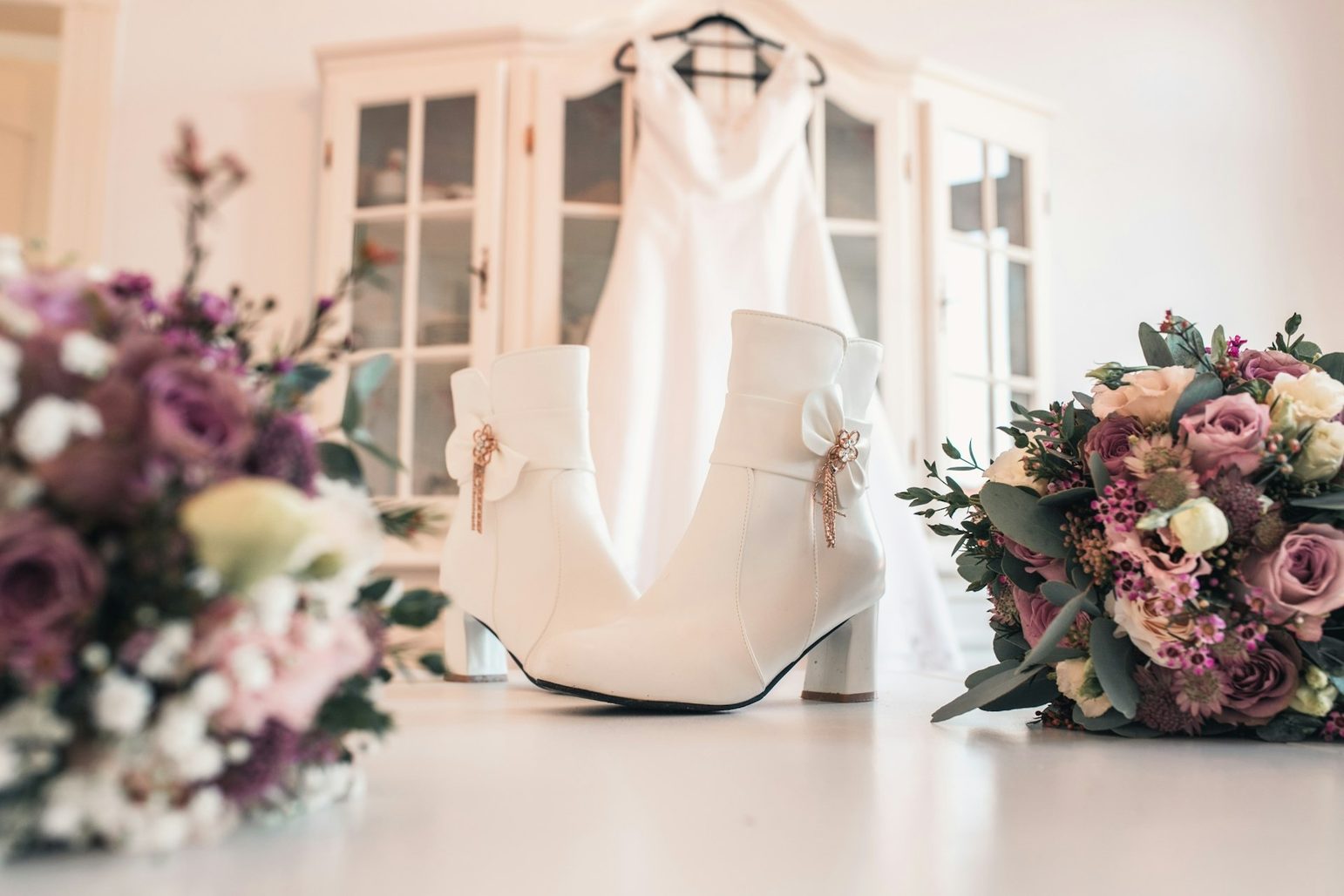 Brautkleid auf dem Bügel, davor Brautschuhe und zwei Sträuße Brautkleid auf dem Bügel, davor Brautschuhe und zwei Sträuße